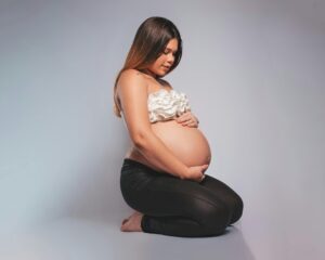 Pregnant woman sitting on the floor with her hands on her belly