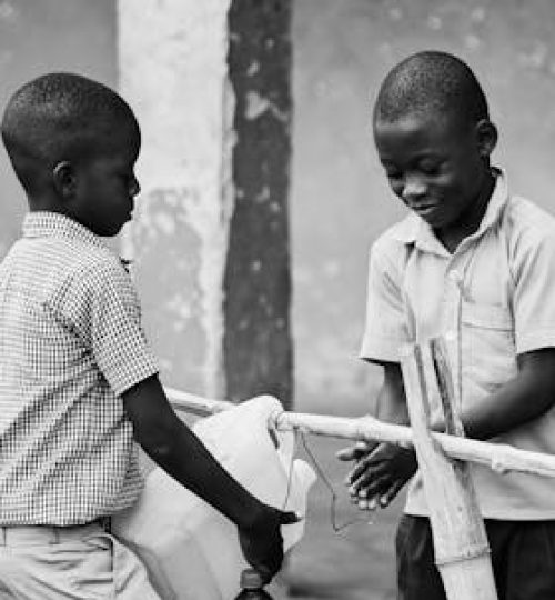 Children Washing Hands From a Bottle on a Rack